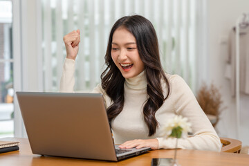 Entrepreneur beautiful business asian young woman working online with laptop and celebrating at home with her work success cheerful and happiness. Small Business Startup concept. Surprise and excite