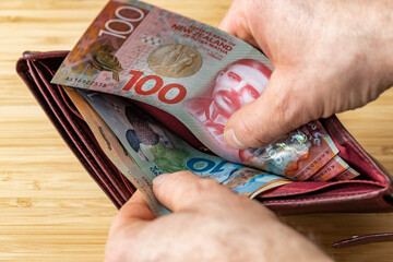 Hand takes money out of wallet, New Zealand Banknotes, Concept, rising prices, purchasing value of New Zealand dollar