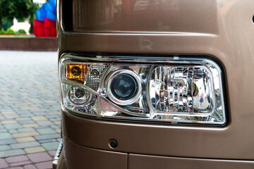 A big truck on the road. Modern new halogen headlights on a truck. Truck headlights.  Square red headlight and reflector on the back of the hood. Car detail, close-up.
