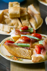 plate with bruschetta of bread, prosciutto, cheese with herbs and cherry tomatoes. Vertical