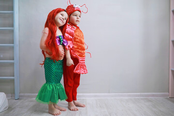 Children in smart carnival costumes on a plain background. Costume of sea fairy creatures. Mermaid and crab.