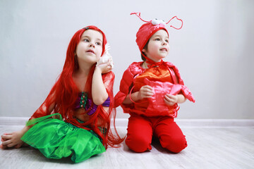 Children in smart carnival costumes on a plain background. Costume of sea fairy creatures. Mermaid and crab.