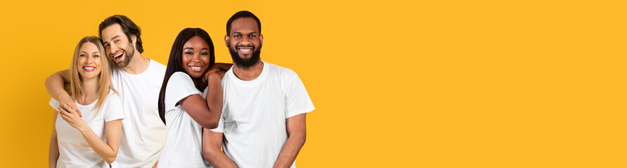 Fototapeta premium Happy young caucasian and black couples embracing on yellow
