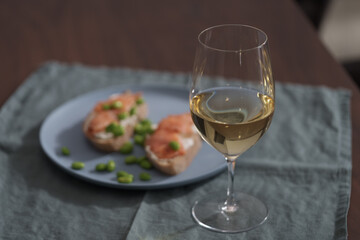 Bruschettas with cream cheese and salmon with glass of white wine on dining table