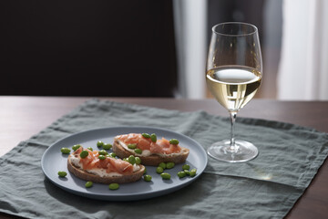Bruschettas with cream cheese and salmon with glass of white wine on dining table