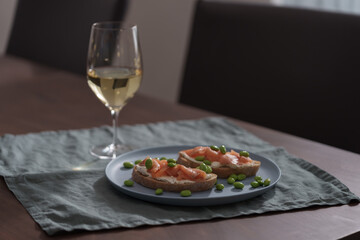 Bruschettas with cream cheese and salmon with glass of white wine on dining table