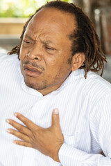 Fototapeta premium Sick middle age African black man with heart attack or chest pain