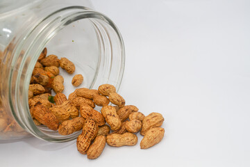 Peanuts coming out of a glass jar. Isolated on white background