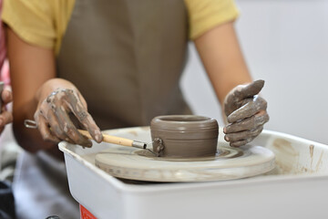 Close up and Cropped image with Potter working on potters wheel making ceramic pot from clay in Pottery workshop.