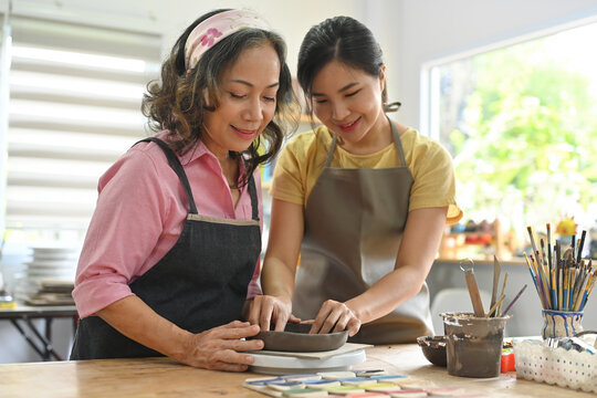 Portrait with An aged-looking pottery teacher teaching student how to make a bowl, Workshop studio, Making traditional pottery.
