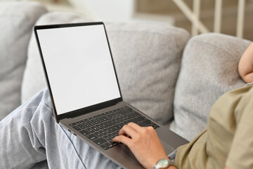 Close up or Cropped image of Young Asian woman using laptop for online learning, E-learning, watching movie, Empty screen of laptop while lying on sofa.