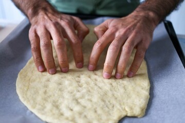 Closeup shot of human hands making dough on the table