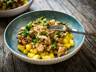 Fried pork loin in creamy sauce with gnocchi and mushrooms on wooden table
