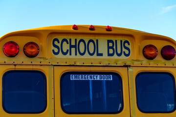 Top of a yellow school bus with lights and text. Closeup against blue sky in the fall. Back to school concept. Copy space. High quality photo