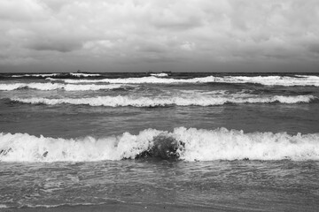 Panoramic view from the beach on the waves of the North Sea with a number of fishing boats in the distance.