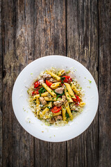 Roasted chicken nuggets, cherry tomatoes, spinach and penne served on wooden table
