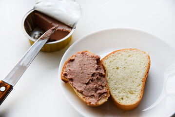 Meat pate and bread with a knife. Spreading pate with a knife on bread on a white background.