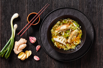 Asian Potstickers Soup in black bowl, top view