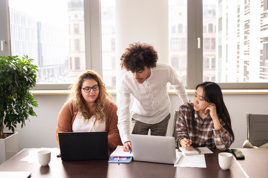 Concentrated group of young people work in a office, with laptop