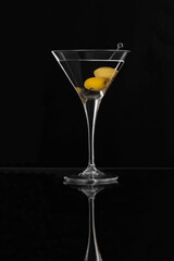 Martini glass with olives on black background