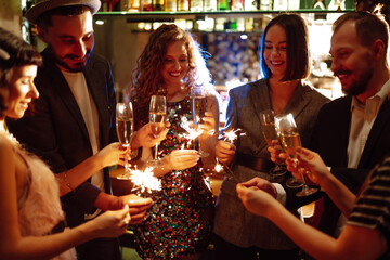 Sparkling sparklers in the hands of friends.Group of people holding sparklers at party. Winter holidays, vacation, relax and lifestyle concept.