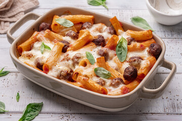 Pasta baked with meatballs and cheese in a skillet on a light slate, stone or concrete background..Top view.