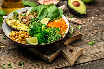 vegetable vegetarian buddha bowl avocado, mushrooms, broccoli, spinach, chickpeas, pumpkin on a wooden background. top view
