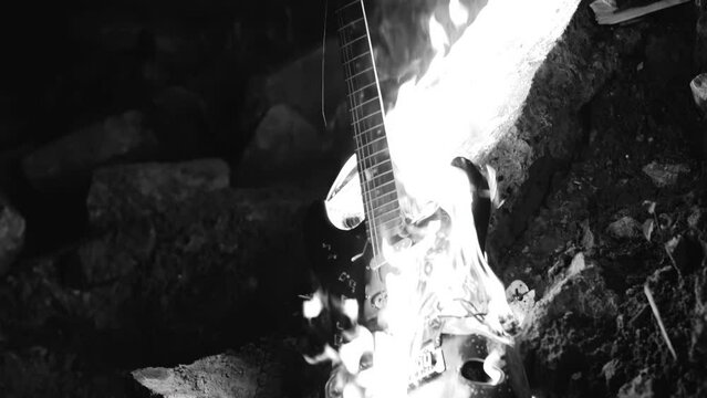 Black and white shots of a burning electric guitar that lies on the ground engulfed in flames. Shooting in slow motion