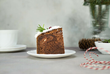 A piece of Christmas cake on plate on grey table with cup of tea.