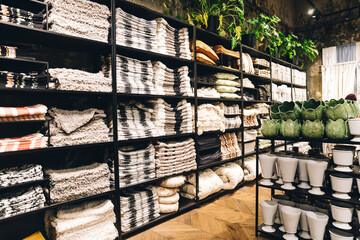 View of assortment of decor for interior shop in store of shopping center. View of shelving with pillows, plaid, blankets, towels. View of home accessories for bathroom, bedroom in shop fashion retail