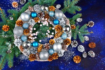 Christmas wreath with pine cones and decorations on a blue background