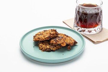 Isolated shot of a plate of oatmeal treats and a glass of drink on a white background
