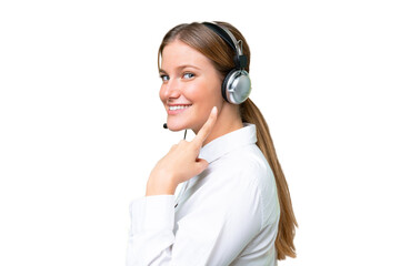 Fototapeta premium Telemarketer caucasian woman working with a headset over isolated background and pointing it