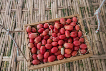 Organic red cherry tomatoes hanging on wooden tray for sale