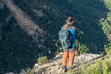 Obraz premium Rear view, standing man on a rock taking photos to the landscape