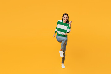 Fototapeta na wymiar Full body young latin woman wear casual cozy green knitted sweater doing winner gesture celebrate clenching fists say yes isolated on plain yellow background studio portrait People lifestyle concept.