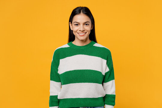 Young smiling happy fun brunette latin woman 30s wear casual cozy green knitted sweater looking camera with toothy smile isolated on plain yellow background studio portrait People lifestyle concept