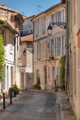 A typical, narrow street in the Provence region of France. A street with building facades in the city of Arles. Summer in the Mediterranean region.