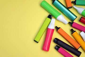 Set of multicolor disposable electronic cigarettes on a bright yellow background.