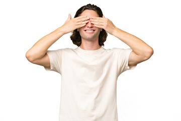 Fototapeta premium Young caucasian man isolated on green chroma background covering eyes by hands and smiling