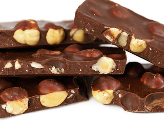 close up of dark chocolate pieces with hazelnuts on white background