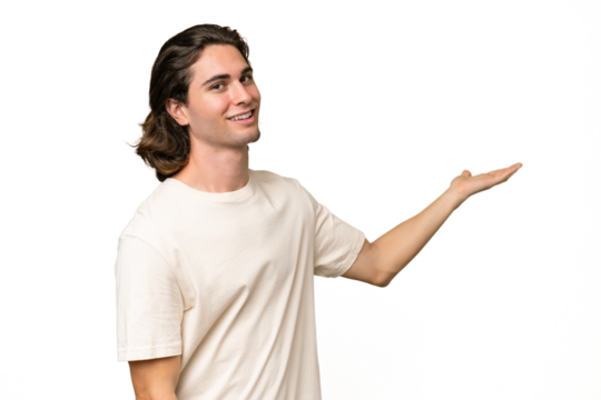 Young caucasian man isolated on green chroma background extending hands to the side for inviting to come