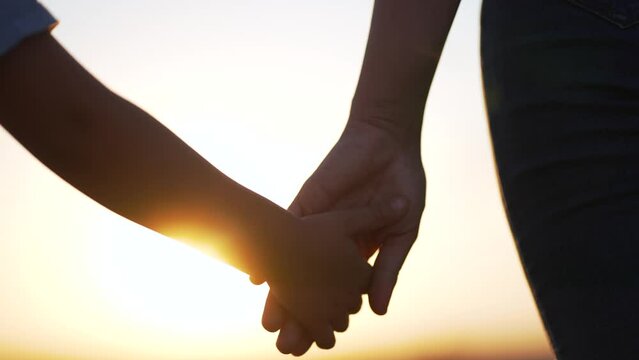 happy family. Mom lends helping hand to her daughter girl in nature in park at sunset. Maternal love and child care. Hand in hand family happiness. Mom and daughter together in nature.Parental support