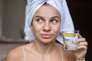 Beauty portrait woman with a towel wrapped around her head  with glass of lemon water 