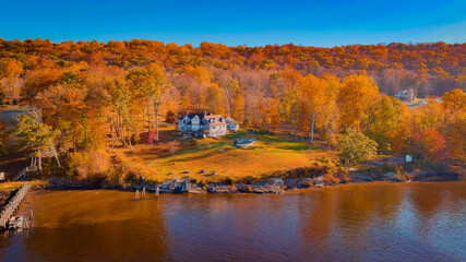 Fototapeta premium Autumn forest on the riverside, marvel at the amazing views of the house on the river bank