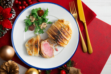 Wellington steak with salad on a table decorated with Christmas motifs.