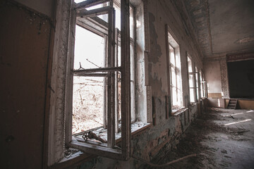 Fototapeta na wymiar Many open windows in an abandoned rural school near the city of Pripyat, Chernobyl region, exclusion zone, Ukraine