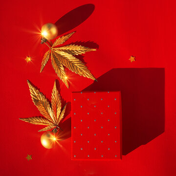 Festive red christmas background with golden marijuana leaf and gift box