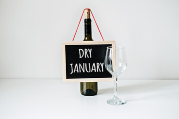 Dry January. Alcohol-free challenge, Health campaign urging people to abstain from alcohol for the January month. Bottle of wine, glass and sign with text Dry January