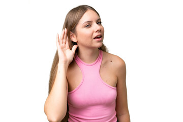 Young beautiful blonde woman over isolated background listening to something by putting hand on the ear